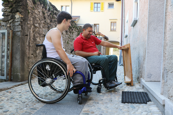 Zwei Rollstuhlfahrer betrachten gemeinsam eine Rampe.