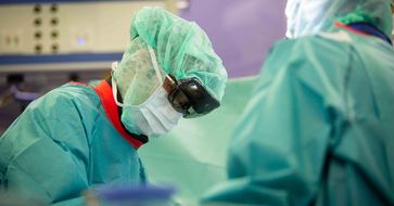 Operationssaal: Zwei medizinische Fachkräfte beim Operieren. Einer der beiden trägt eine holografische Brille