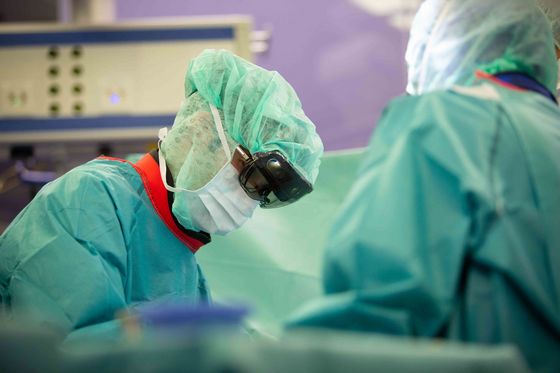 Operationssaal: Zwei medizinische Fachkräfte beim Operieren. Einer der beiden trägt eine holografische Brille